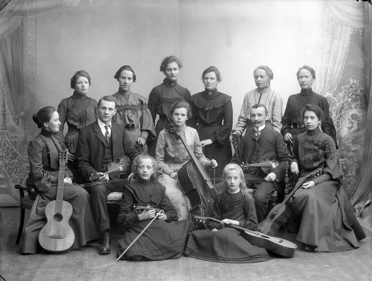 Gustav Borgen, Stor gruppe musikere, voksne og barn, med instrumenter. Feler, cello og gitarer. Familieorkester? Tapetserer J. Larsen.