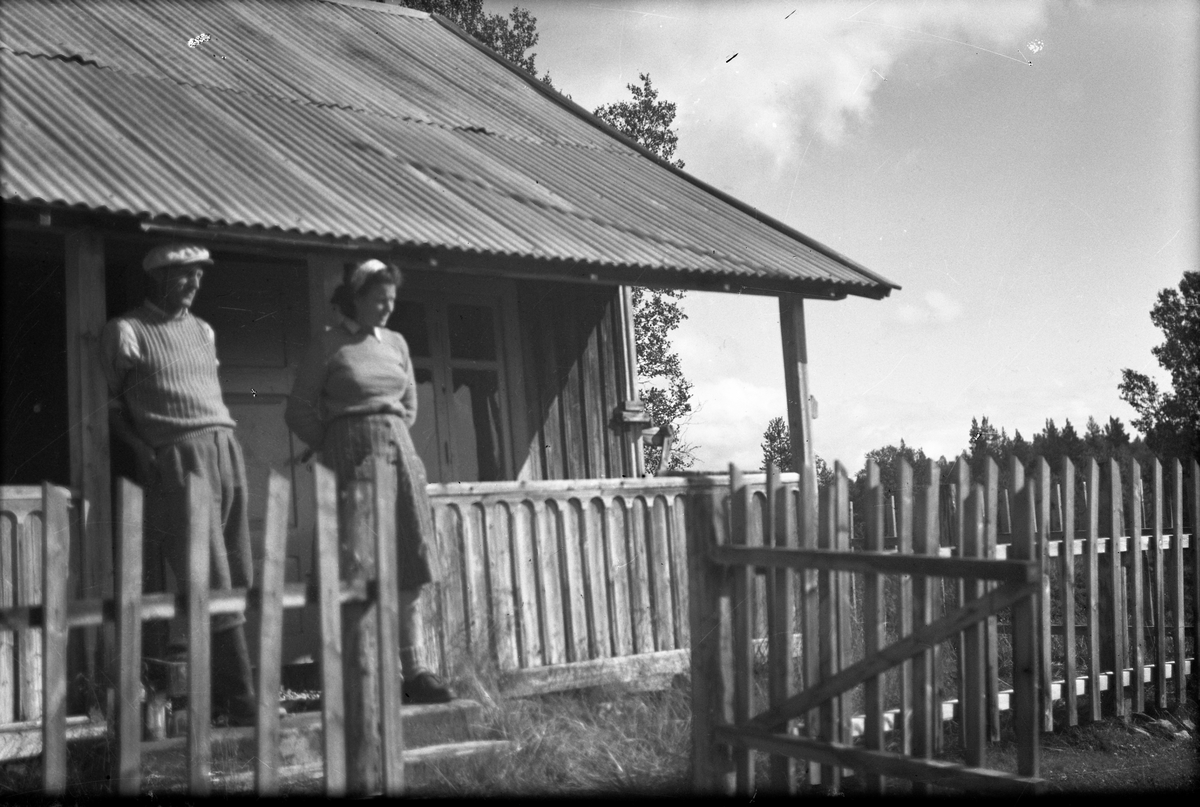 Anders O. Sørhuus, Mann og kvinne foran hytte, stakitt