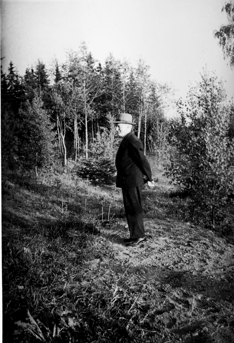 Anno Domkirkeodden, Landhandler Ludvig Grønnerud (1890-1984) i Dalby, Helgøya. Spaserer i skogen.