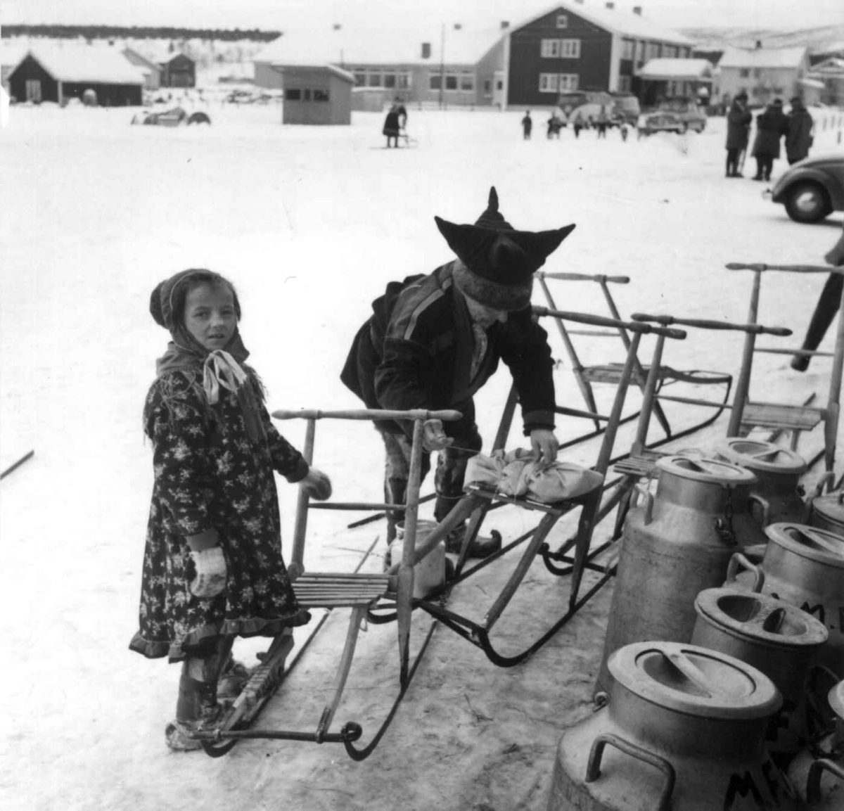 Virginia Raymond Davidson, Barn med spark utenfor Samvirkelaget, melkespann i forgrunnen. Karasjok 1958.