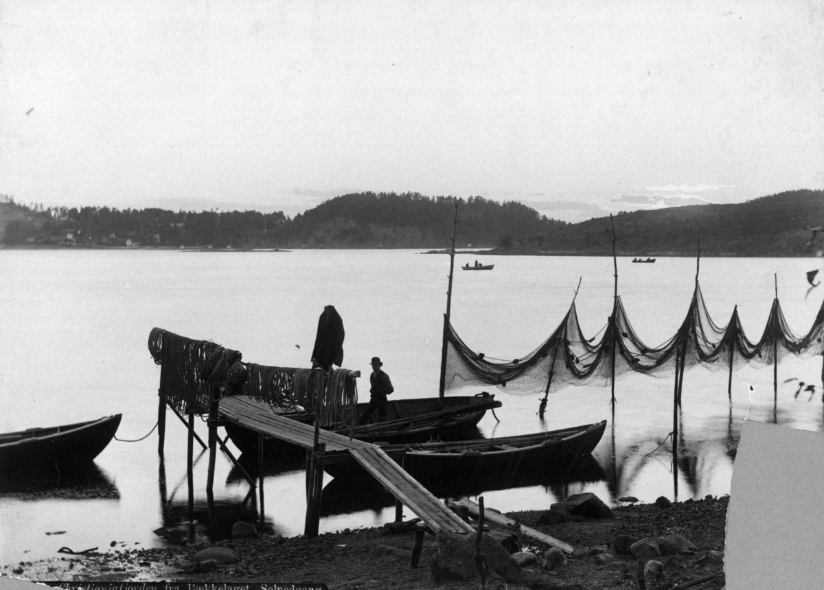 Axel Lindahl, Bekkelaget, Oslo. Mann i båt ved brygge og fiskegarn.
