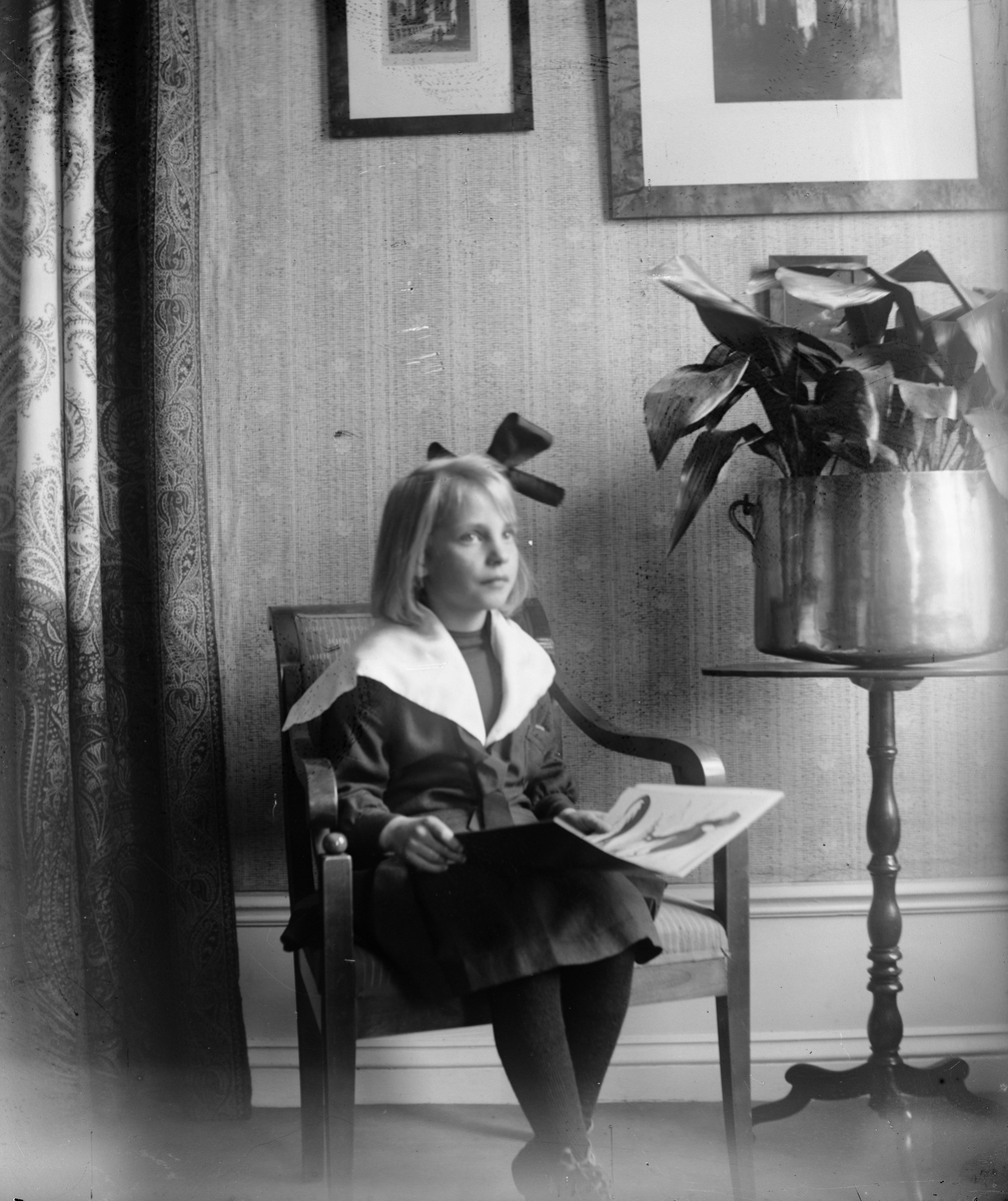 Okänd,, Ruben Liljefors dotter Marit sitter på stol och läser bok i hemmet, sannolikt i Sverige