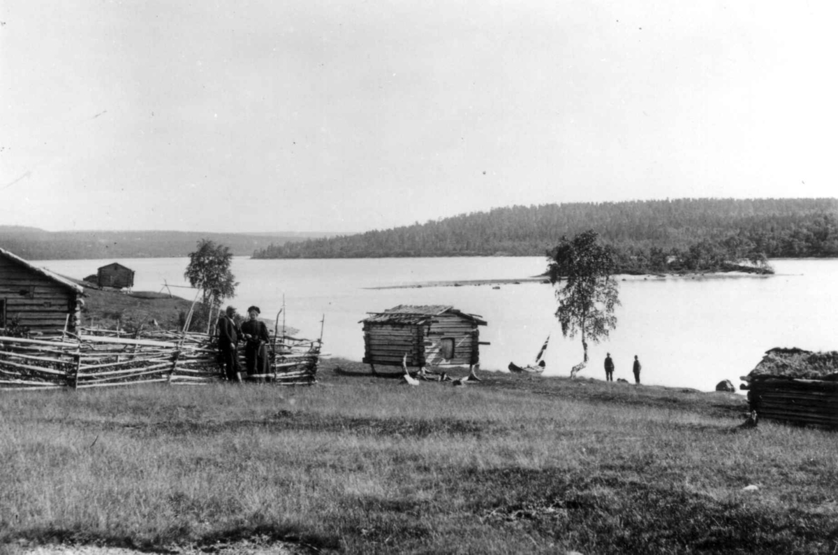 Ellisif Rannveig Wessel, Skolteboplass på Nakholmen, Vaggetem, Finnmark, før 1900. Stabbur ved Pasvikelven. Ellisif Wessel ved gjerdet.