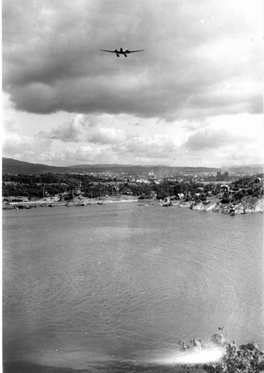 Hermann Christian Neupert, Oslo. Oversiktsbilde. Utsikt fra fjorden mot byen. Øyer med hytter og et fly på himmelen.