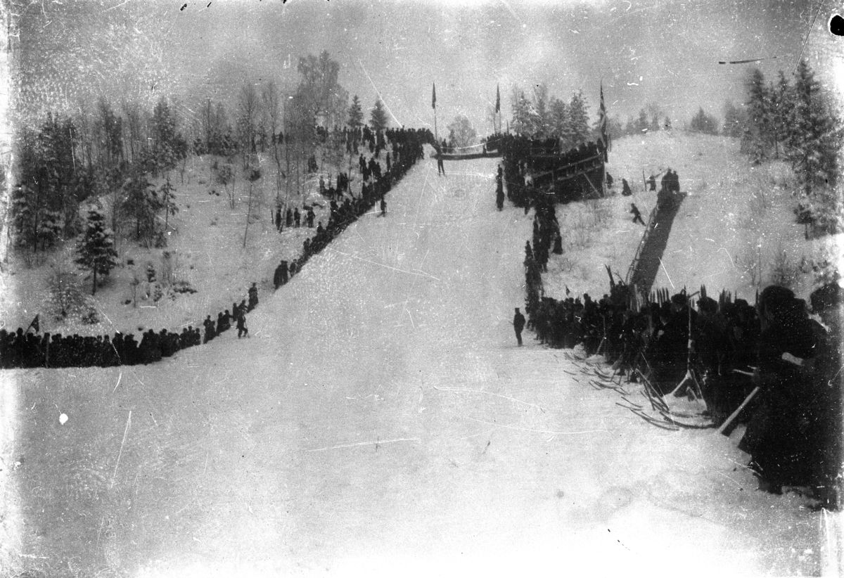 Johannes Larsen Alhaug, Hopprenn i Frambakken i Brumunddal. Publikum på sletta ser på en skihopper.