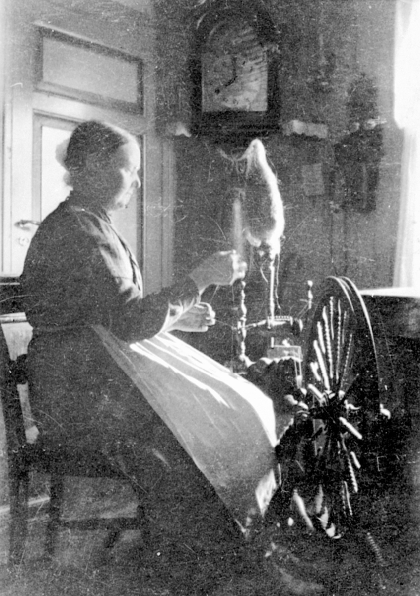 Anno Domkirkeodden, Johanne Kinde (1860 - 1948) spinner lin på linrokk. Interiør, veggklokke, telefon på Kinne Brøttum, Ringsaker.