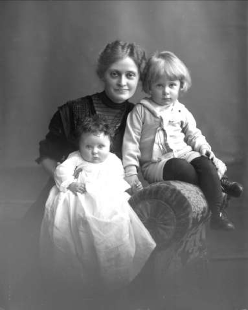 Gustav Borgen, Gruppeportrett, kvinne i stol med to barn på fanget, et spedbarn og et i matrosdrakt. (Frøken Platou.)