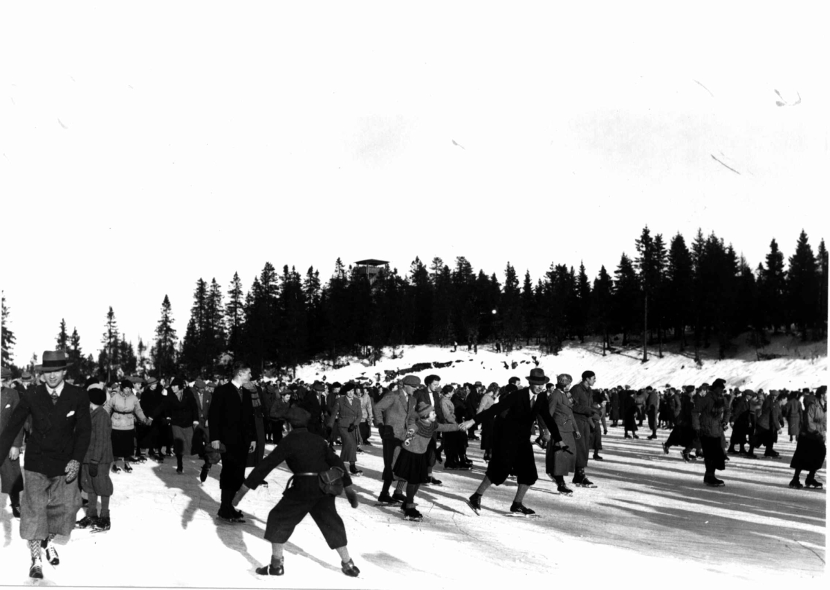 Hermann Christian Neupert, Tryvann skøytebane, Oslo. 1934. Tettpakket med skøyteløpere på isen. Toppen av Tryvannstårnet ses i bakgrunnen.