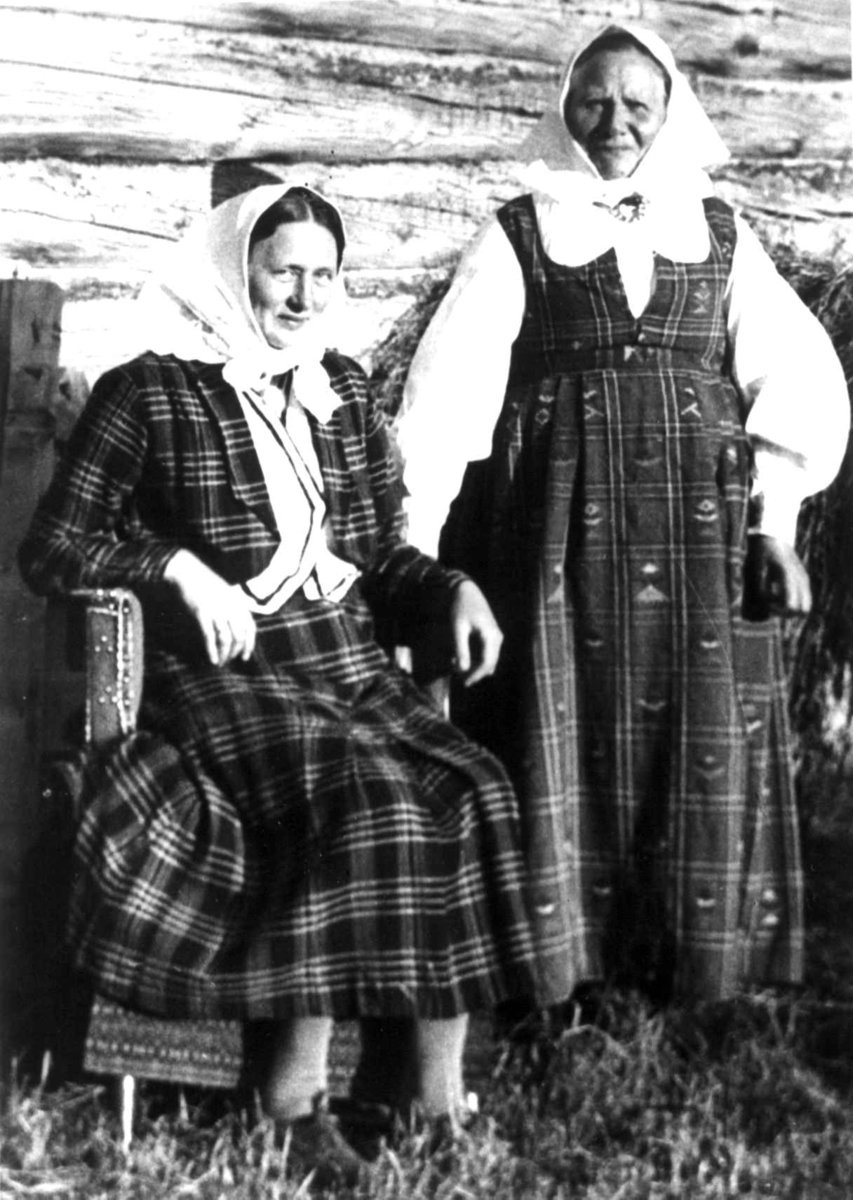 Anna Grostøl, Antagelig Lesja, Oppland 1934. To ukjente kvinner i kvinnedrakter utenfor en husvegg.