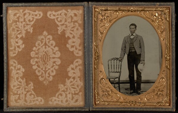 Unknown, [Full-length Portrait of a Man Standing with a White Hat Next to a Chair]