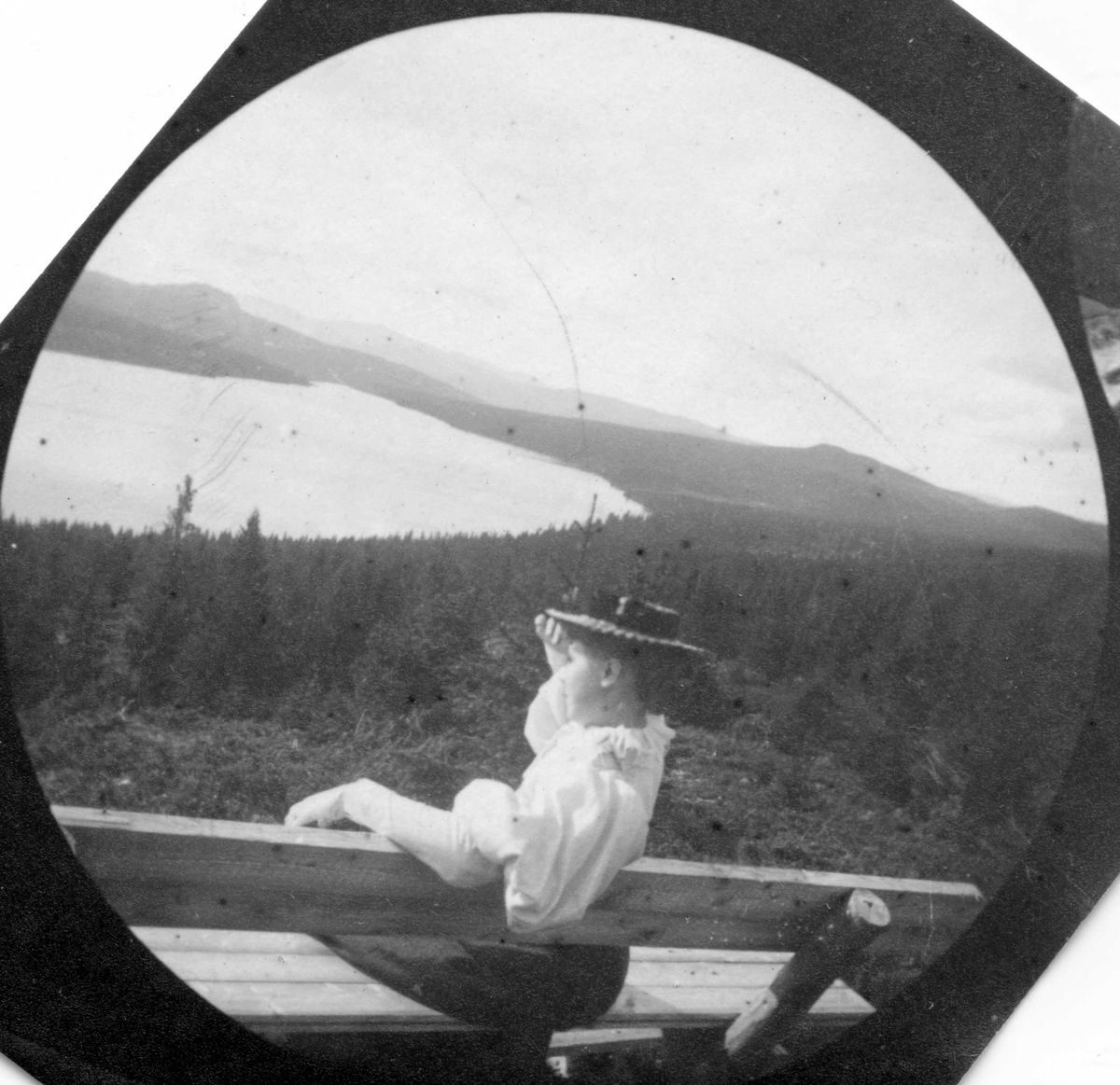 Fredrik Carl Mülertz Størmer, Golå, Sør-Fron, Oppland. Frk. Olga Schiøll sitter på krakk med utsikt over skog og vann.
