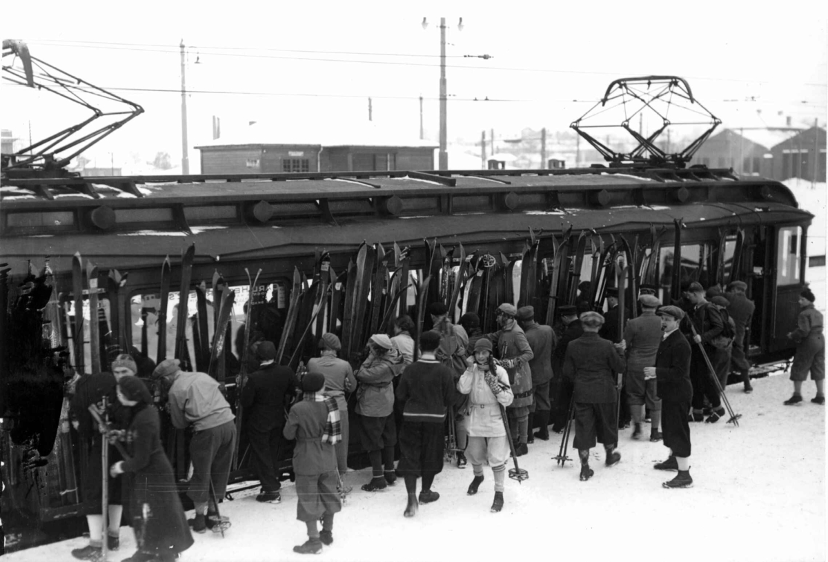 Hermann Christian Neupert, Oslo. Skisøndag med Holmekolltrikken. 1933. Majorstuen stasjon. Skiløpere spenner skiene fast til trikken.