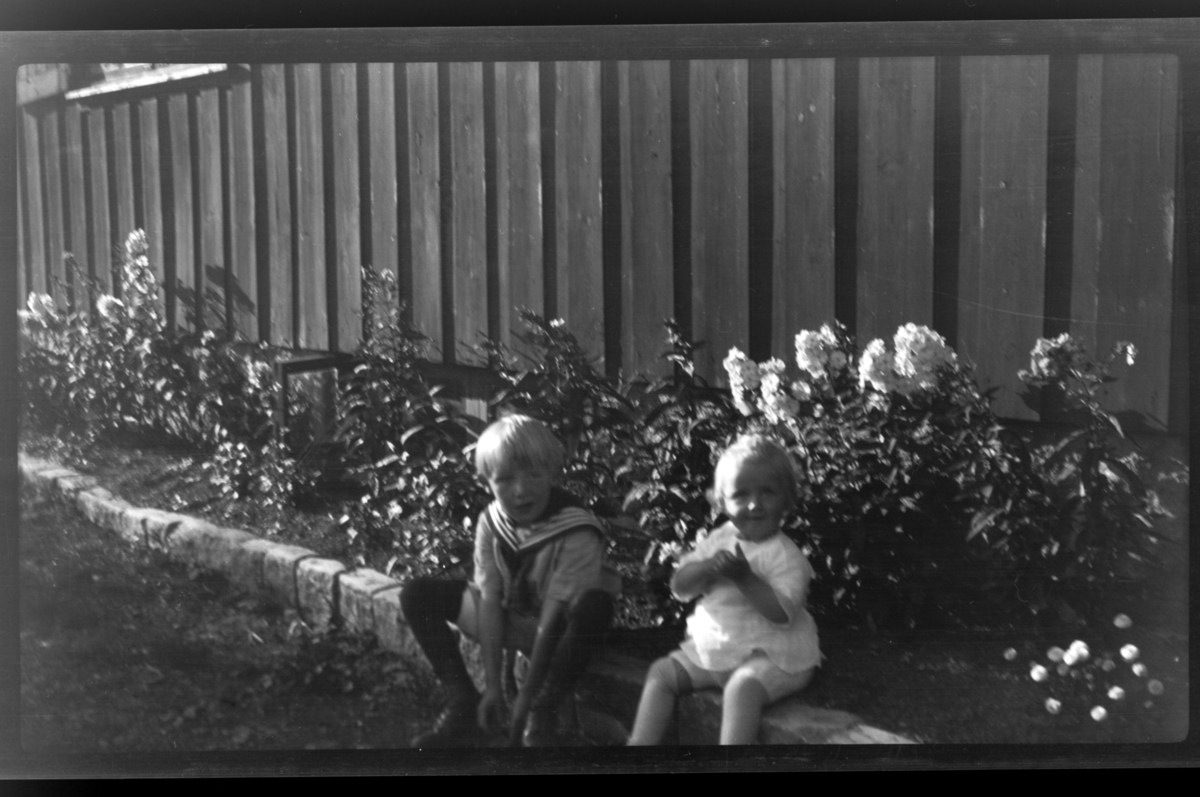 Rolf Sr. Sundt, Brødrene Rolf jr. og Julius Sundt sitter sammen ved et blomsterbed, Villa Knyggen, Voksenlia. Fotografert 1922.