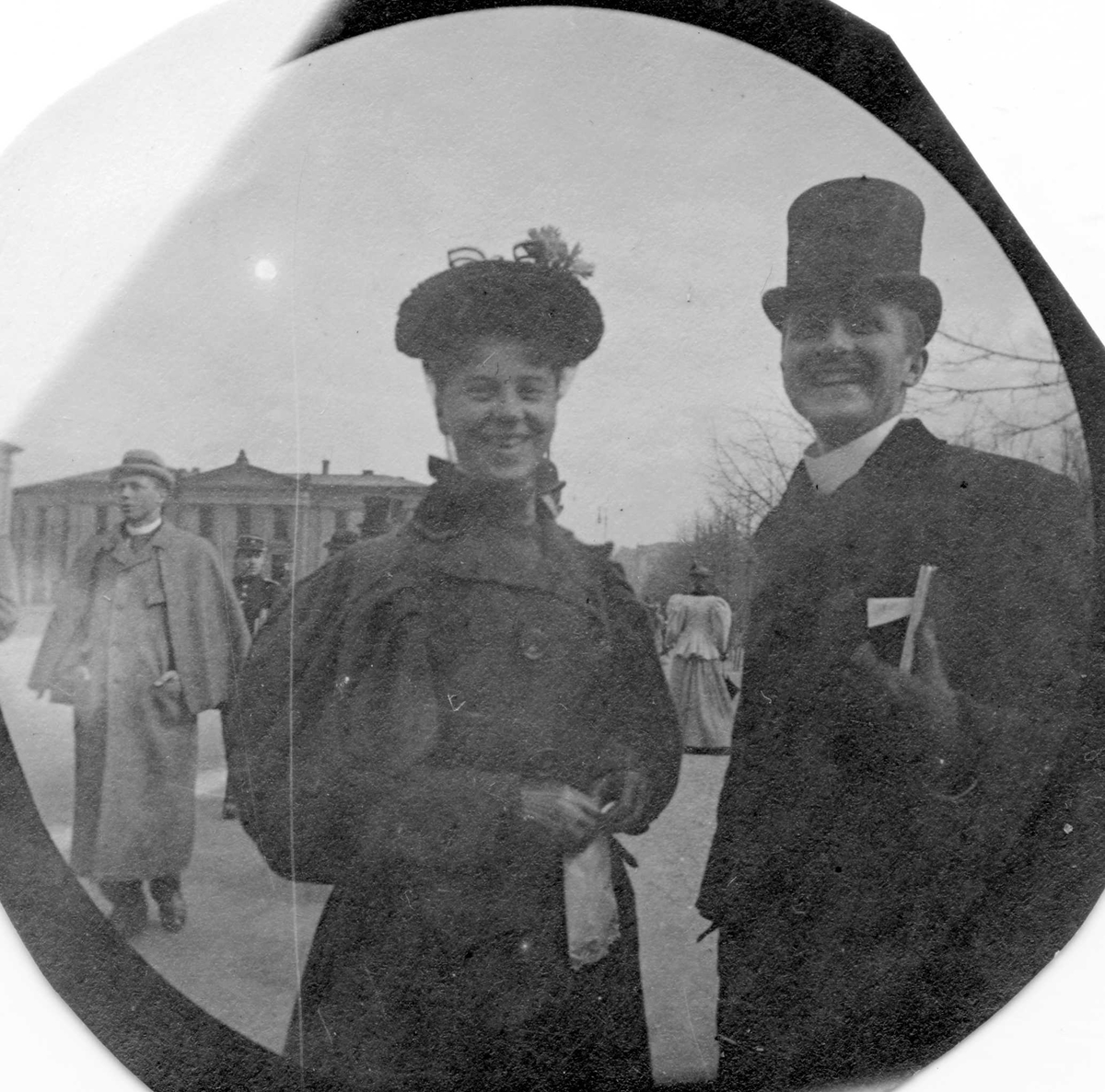 Fredrik Carl Mülertz Størmer, Frk. Marie Reimers og Petter Anker samt hr. Wischmann, bak t.v., student fra 1892, spaserer langs Karl Johans gate, Oslo, Universitetet på den andre siden av gata.