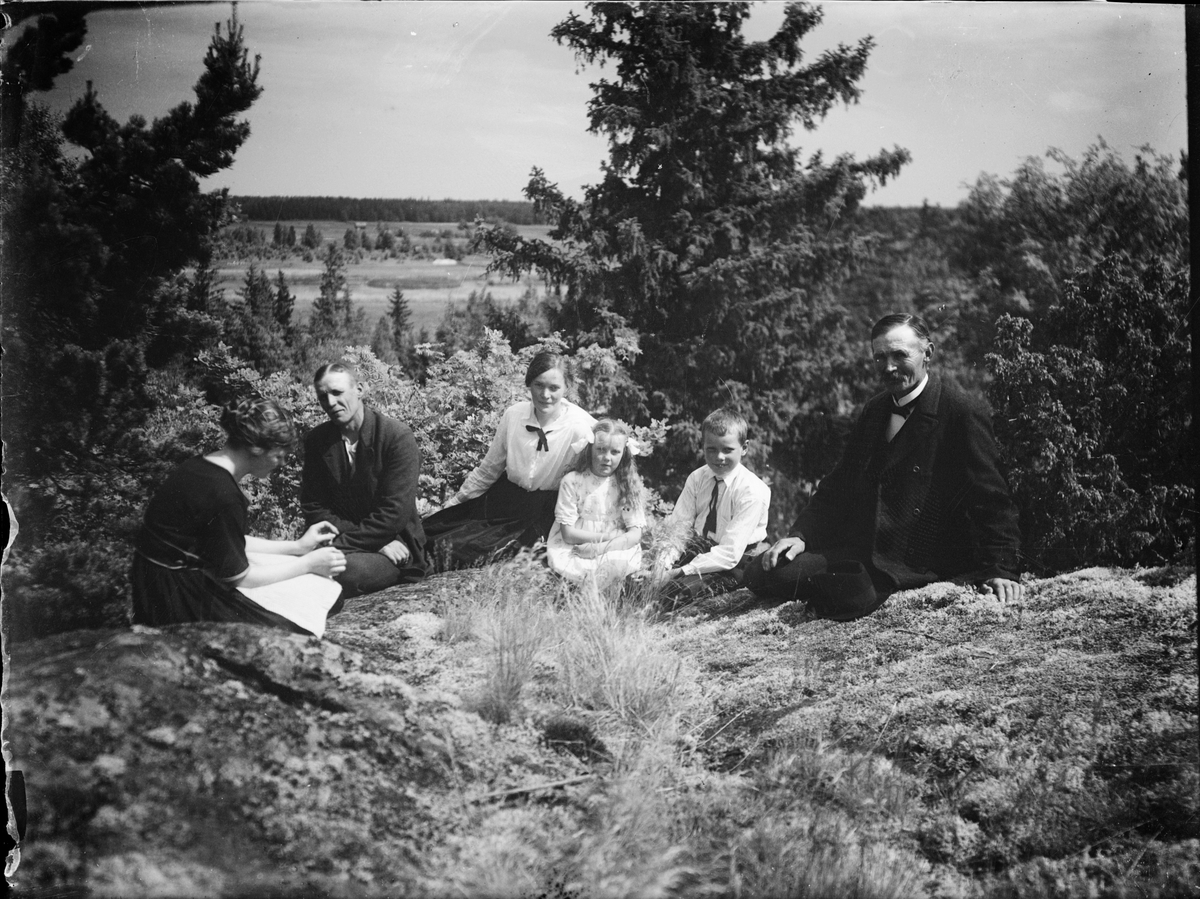 Skötsner-Edhlund, Woman, man and child sitting on a “mountain skull,” Östhammar, Uppland