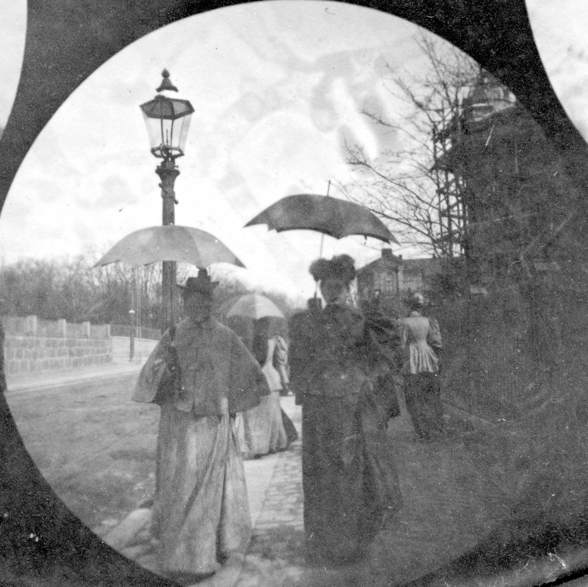 Fredrik Carl Mülertz Størmer, Frk. Agnes Hvistendahl og en annen kvinne spaserer langs bygate, ant. Oslo, med park på den ene siden og bygårder på den andre.