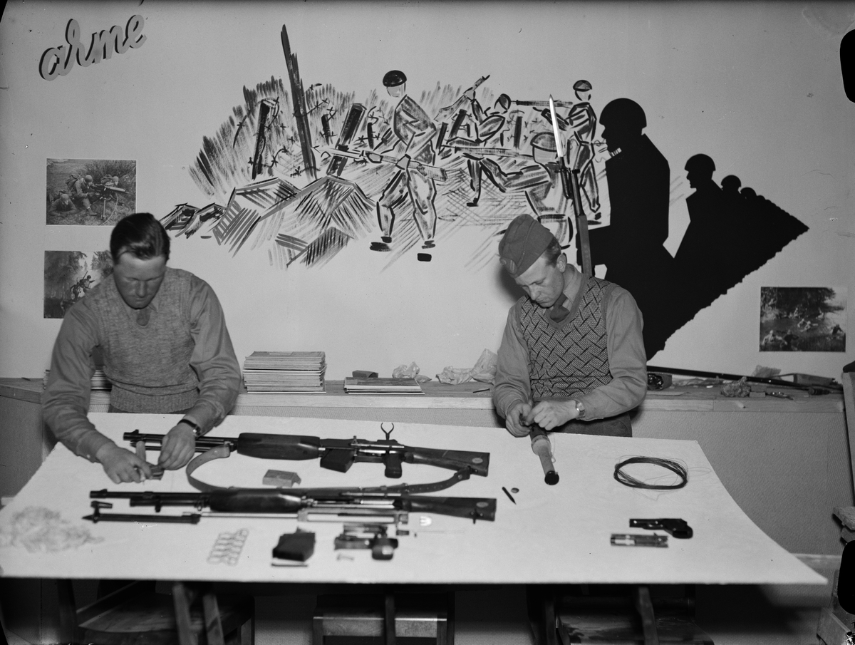Paul Sandberg, Fänrik Sven Torslow och löjtnant Georg Wally från Upplands Regemente håller på med att "ordna utställningen av lättare infanterivapen" i "Landsbygdens försvarsutställning", Svartbäcksgatan 25