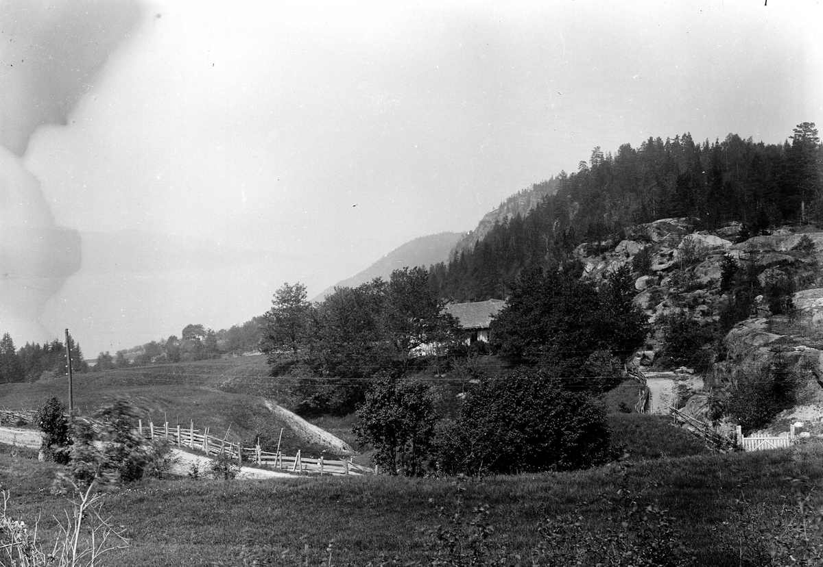 Juliane Fredrikke Langberg, Fra Hurum, utsyn over landlig område med fjord i bakgrunnen. Veiparti med gjerde og grind. Fotografens svoger var sokneprest i Hurum 1897-1904. Fra malerinne Juliane Fredrikke Langbergs (1856-1930) samling, tatt ca.1895-1910 med motivkrets slekt og venner samt steder tilknyttet samvær med disse.