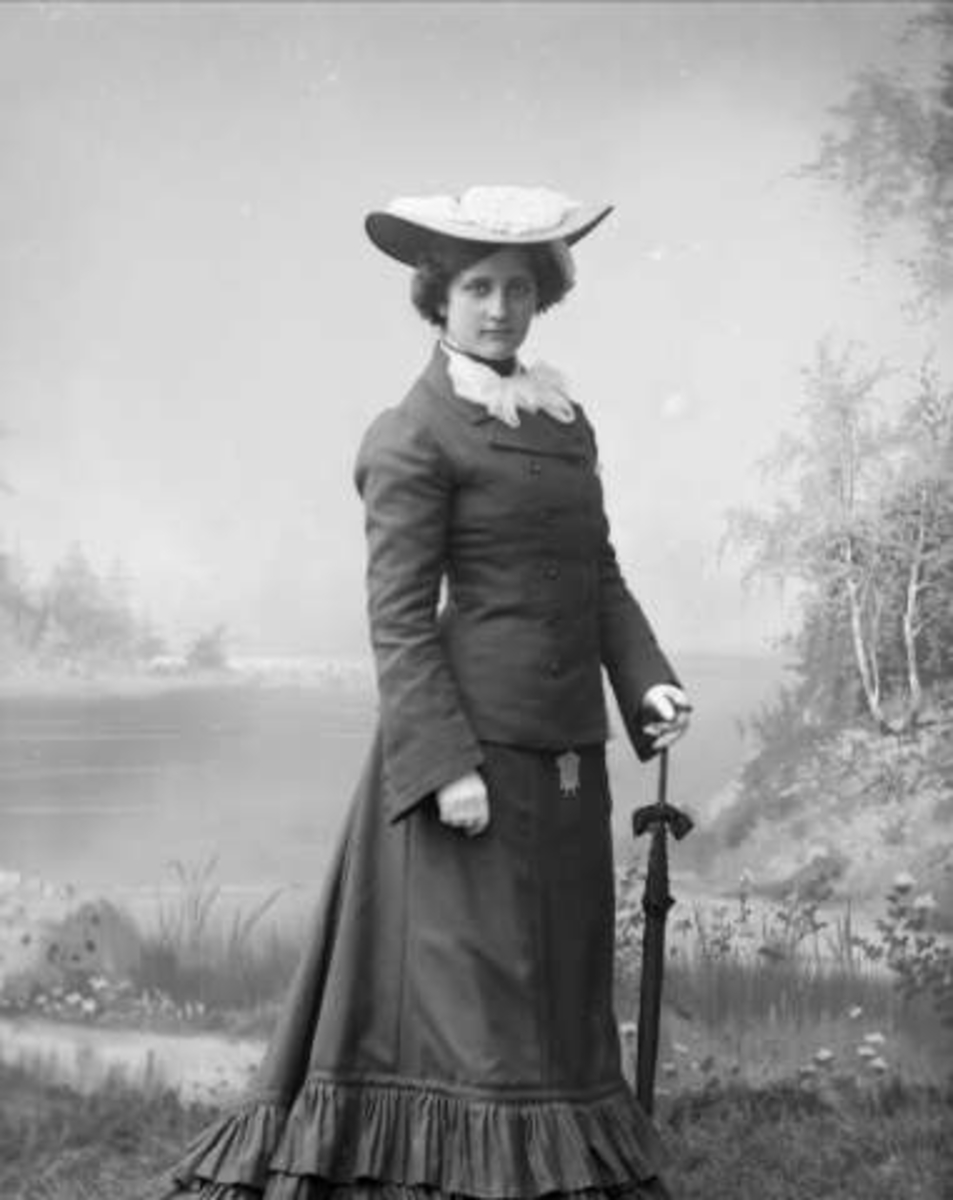 Gustav Borgen, Portrett, kvinne i ytterplagg, med hatt og parasoll. Dagny Andersen.