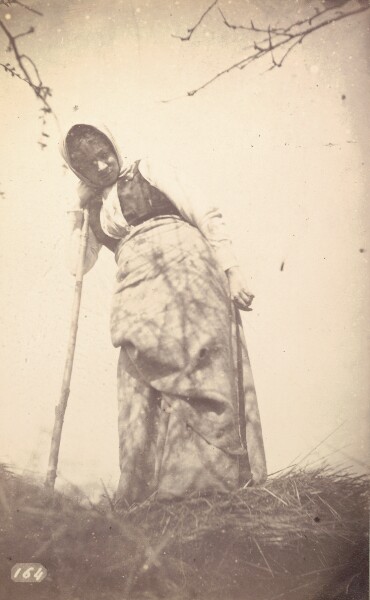 Unknown, [Woman leaning against staff in field]