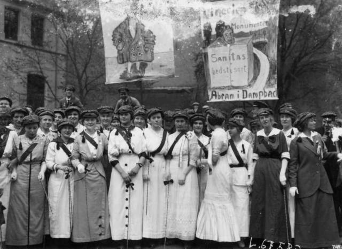 Hermann Christian Neupert, Oslo. Russ 17. mai 1914 - Aars og Voss skole. Festkledde kvinner i lange kjoler. Russeplakater i bakgrunnen.