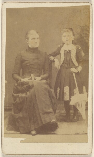 Unknown, [Mother sitting with a book in her lap, girl standing with an umbrella]