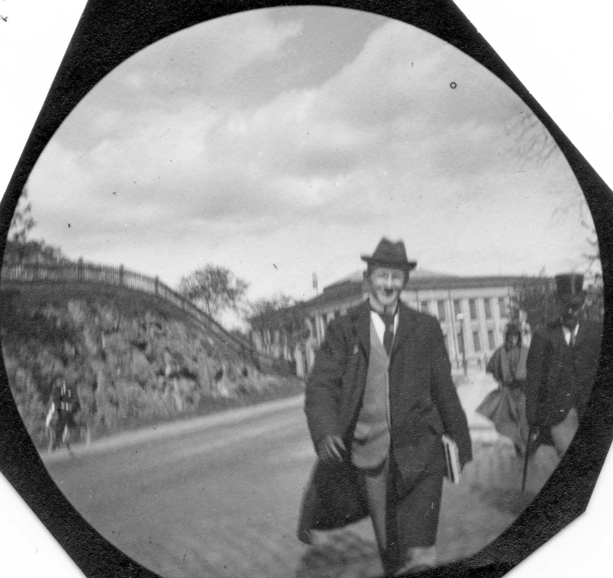 Fredrik Carl Mülertz Størmer, Stud. med. Niels Heitmann spaserer i bygate, Oslo. Universitetet i bakgrunnen, Slottsparken på andre siden av gaten.