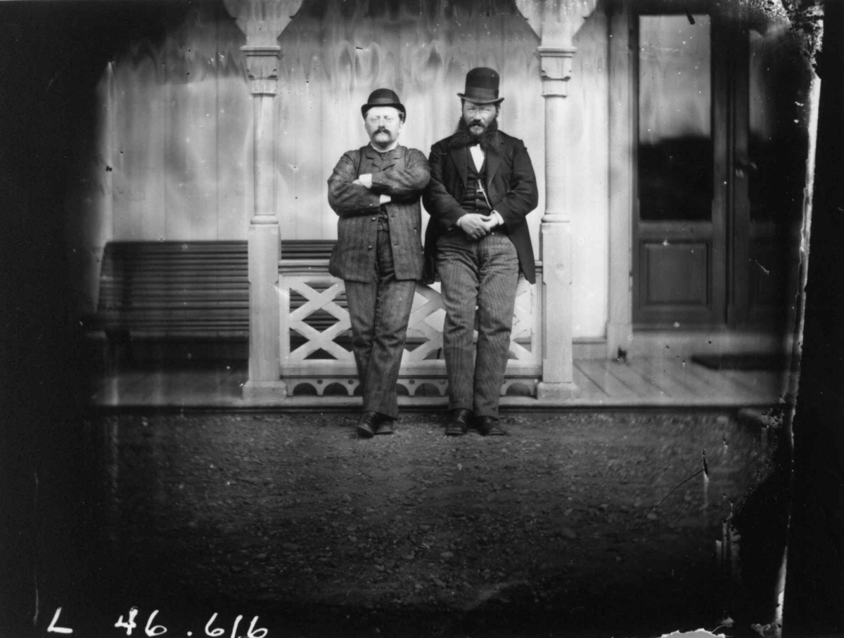 Fredrik Emil Faye, Dobbeltportrett, 2 menn med hatt i søylegang utendørs. Fra portrettserie av personer som bodde på eller besøkte Dal gård, Ullensaker, fotografert av gårdens eier, kammerherre Fredrik Emil Faye (1844-1903) i årene 1875-1900.