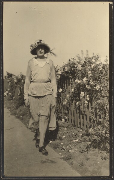 Louis Fleckenstein, [Woman Walking Along Fence with Flowers]