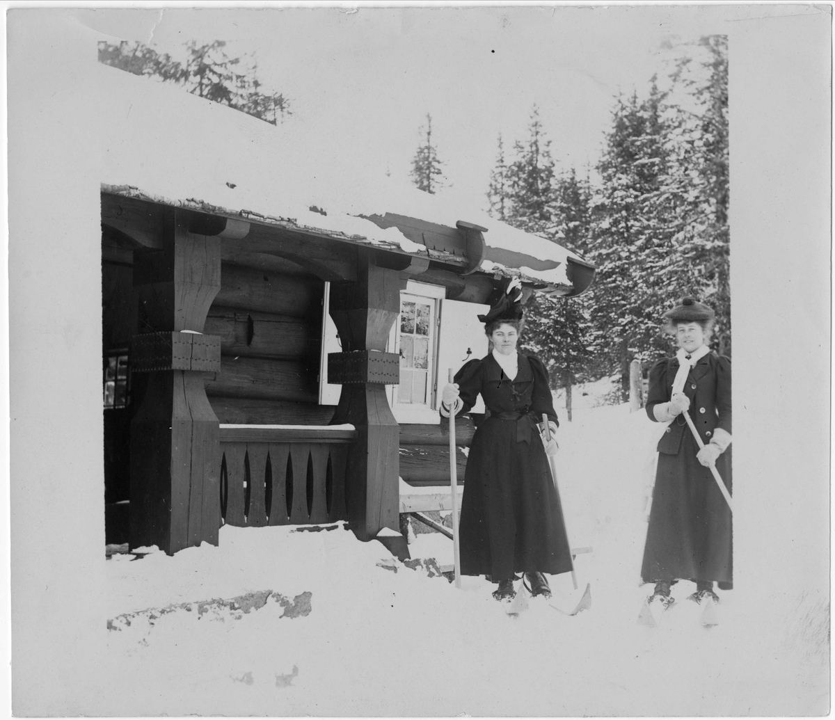 Robert Collett, Kvinner på ski foran bygning, ukjent sted. Serie tatt av Robert Collett (1842-1913), amatørfotograf og professor i zoologi.