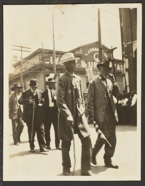 Unknown, [View of Men Walking Down Street]
