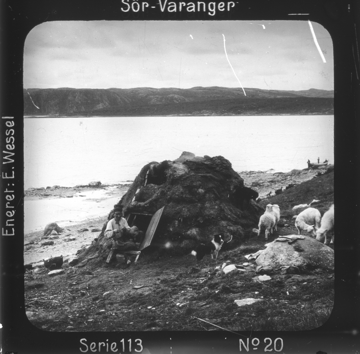 Ellisif Rannveig Wessel, Skoltesamers lakseplass ved Bøkfjorden, Sør-Varanger, Finnmark. Skoltekone med sitt barn i døra til torvgammen. Motivet har nr.20 i lysbildeforedraget kalt "I lappernes land - Sør-Varanger", utgitt i Nerliens Lysbilledserier, serie nr 113.