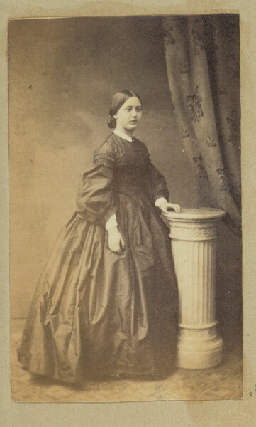 Unknown, [Portrait of woman standing next to pedestal]