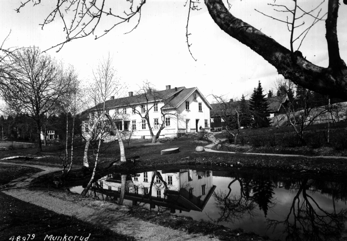 Anders Beer Wilse, Munkerud gård, Oslo, Østre Aker. Husene sett fra hagen med en dam i forgrunnen.