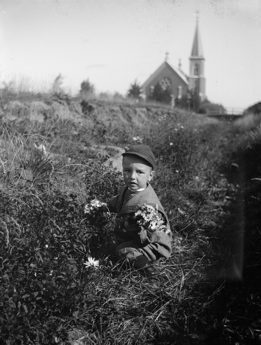 Carl Liljefors, Ivar Liljefors plockar blommor i dike med Mikaelskyrkan i bakgrunden, Svartbäcken, Uppsala 1900 - 1901