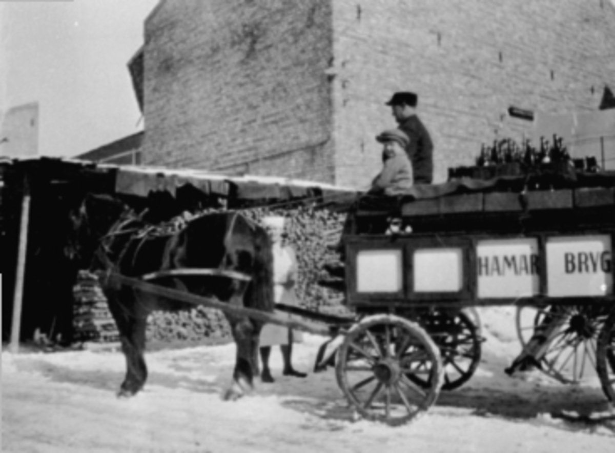 Anno Domkirkeodden, ØLKJØRER GUSTAV GULBRANDSEN, NILS JAHRMANN, PETRA RØHNE, HESTPå bukken på ølvogna sitter ølkjører Gustav Gulbrandsen ogNils Jahrmann. Førstejomfru Petra Røhne ved hesten Balder ibakgården til Grand Hotell