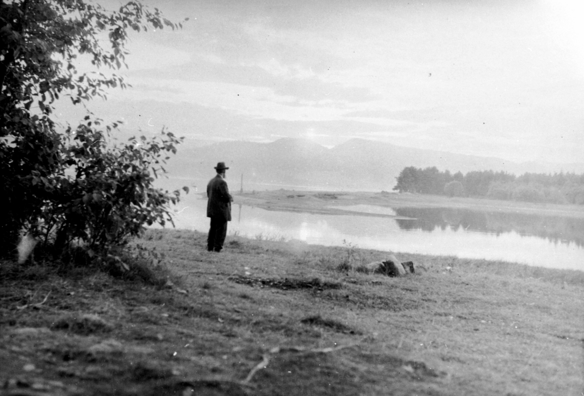 Anno Domkirkeodden, Mann med hatt speider ut over Mjøsa ved Korgstuevika, Moelv, Ringsaker.