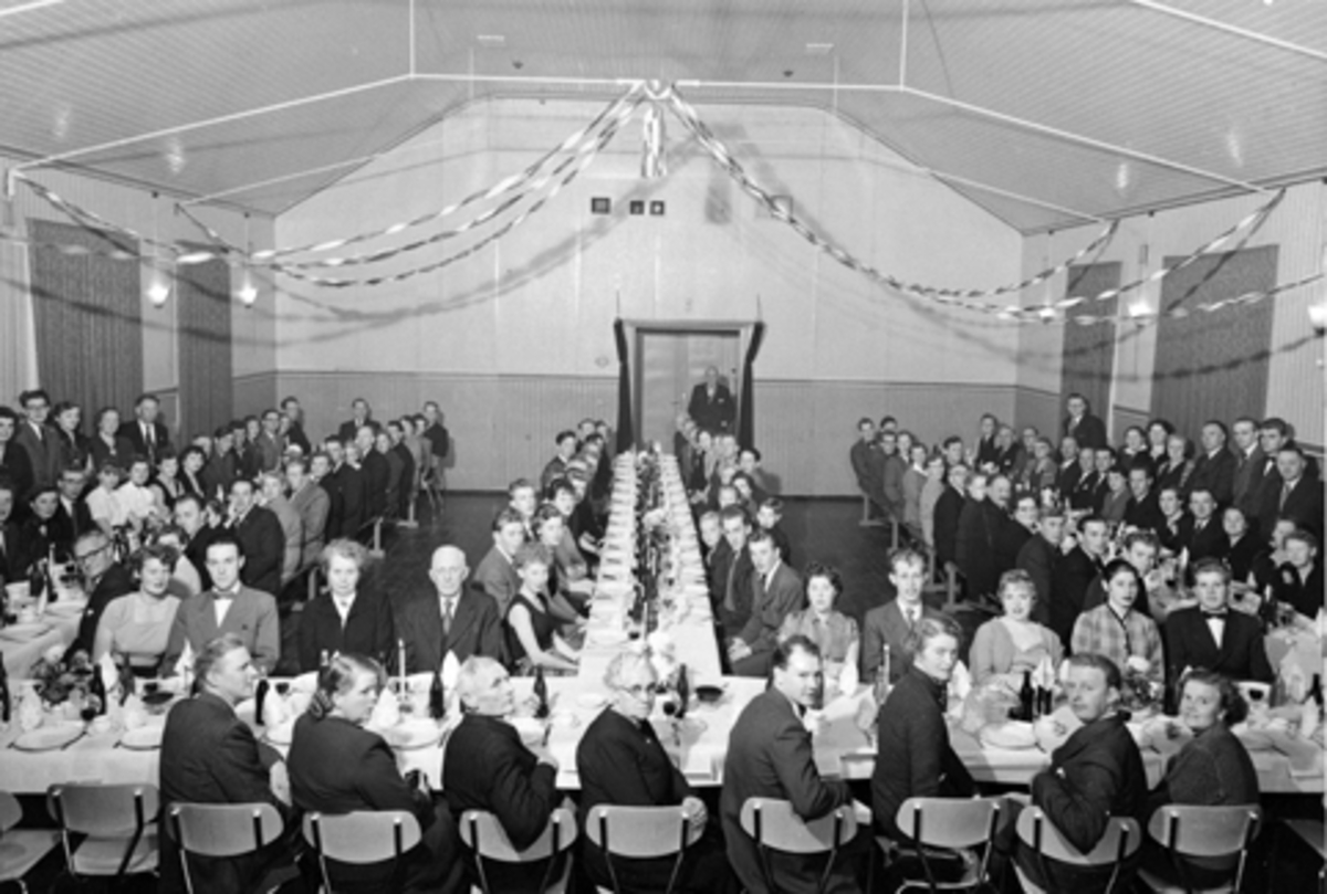 Anno Domkirkeodden, Brumunddal Arbeiderlags 50-års jubileum I Folkets Hus. Lagets medlemmer samlet rundt festdekket bord. Foran til høyre sitter Mildrid og Magne Antonsen, Rakel Sewerin, ukjent, Laura Hagelund, Gustav Gulbrandsen, Synnøve og Kristian Gundersen.