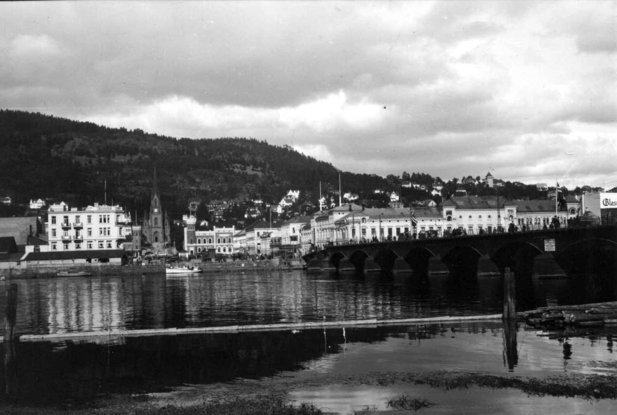 Hermann Christian Neupert, Drammen, Buskerud. 1930. Oversiktsbilde mot Bragernes med Drammenselva i forgrunnen. Bybeggelse. Bybrua til høyre. Bragernes torv med Bragernes kirke i bakgrunnen.