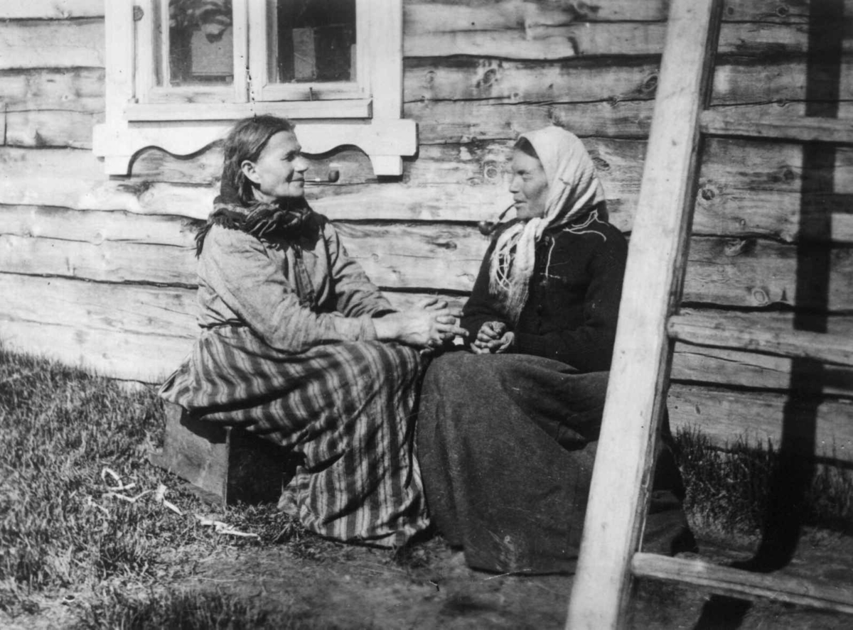 Ellisif Rannveig Wessel, Finske kvinner ved husvegg med piper. Neiden, Sør-Varanger, Finnmark, antatt 1900-1910.