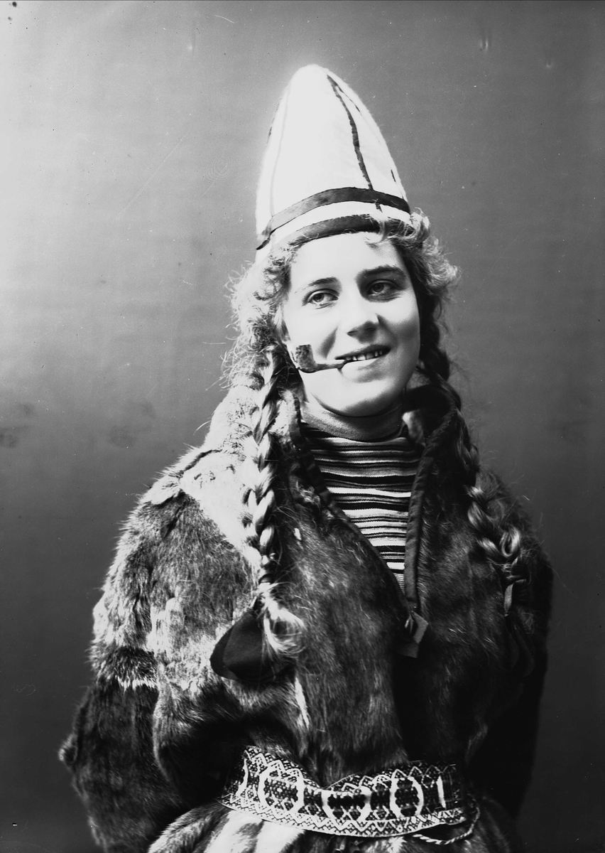 Solveig Lund, Kvinne i sameliknende drakt med pesk og lue. Pipe i munnen.