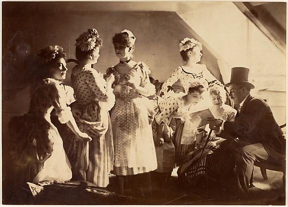 Unknown, [A Group of Six Costumed Women Posed in Interior with Top Hatted Gentlemen]