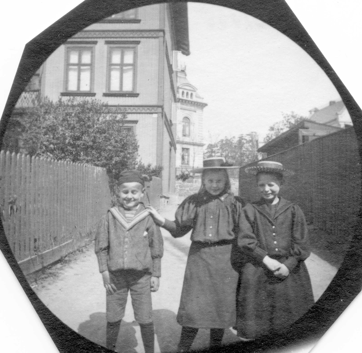 Fredrik Carl Mülertz Størmer, To jenter og en gutt i boliggate, Vestheimgaten, Oslo, med gjerde, hage og stort trehus. Betty Reimers i midten.