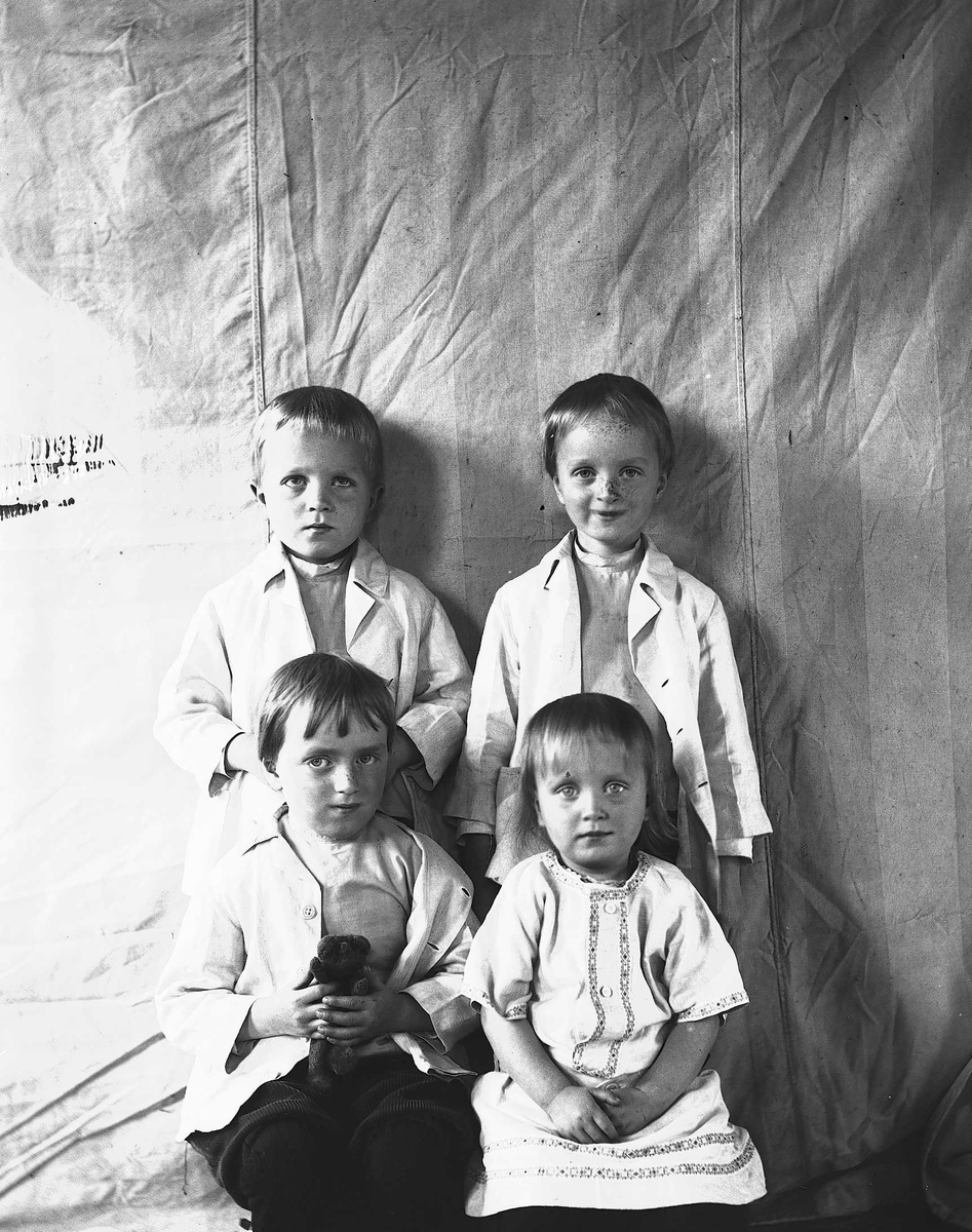 Axel Quinsgaard Wiborg, Portrett av fire barn, fotografert mot opphengt bakteppe, ukjent sted. Antatt er de barn i familen Axel Q. Wiborg.