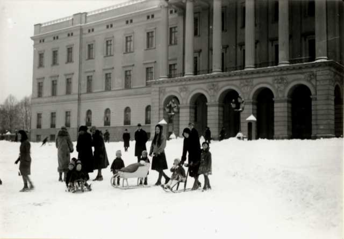 Hermann Christian Neupert, Slottet, Oslo. 1930. Vinterbilde. Kvinner og barn med sparkstøttinger på Slottsplassen.