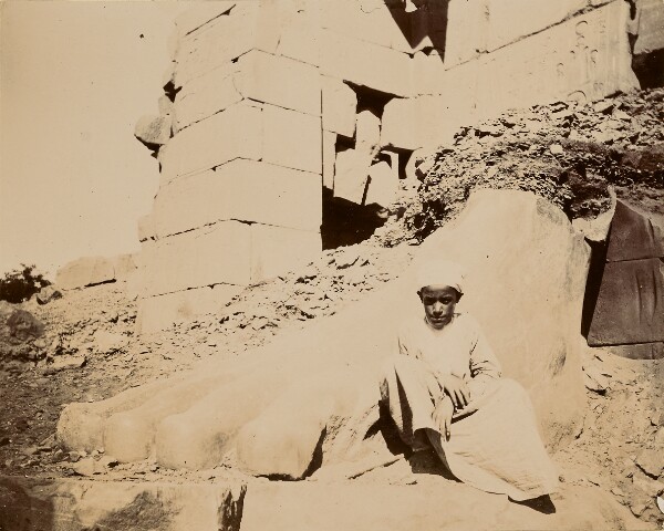 Unknown, [Young man sitting at base of sculptural ruins]