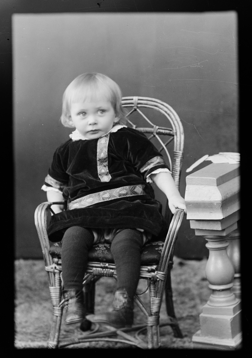 Skötsner-Edhlund, Ateljéporträtt - ett barn sitter i en korgstol, Östhammar, Uppland