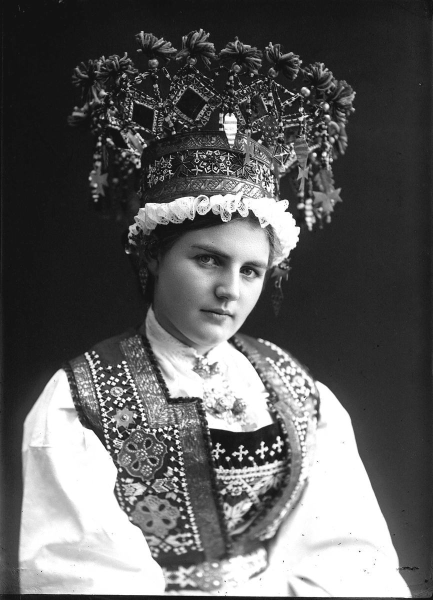 Solveig Lund, Studiofotografi av kvinne med brudedrakt og brudekrone fra Voss i Hordaland. Sittende. Bryst/hofteutsnitt. Vendt mot høyre. Ser ut av bildet.
