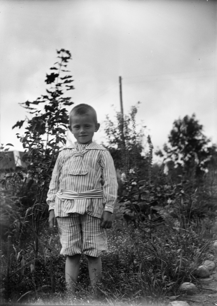Okänd,, Sannolikt Alf Liljefors, son till Christiane och Ruben Liljefors, står ute i trädgård, sannolikt i Sverige