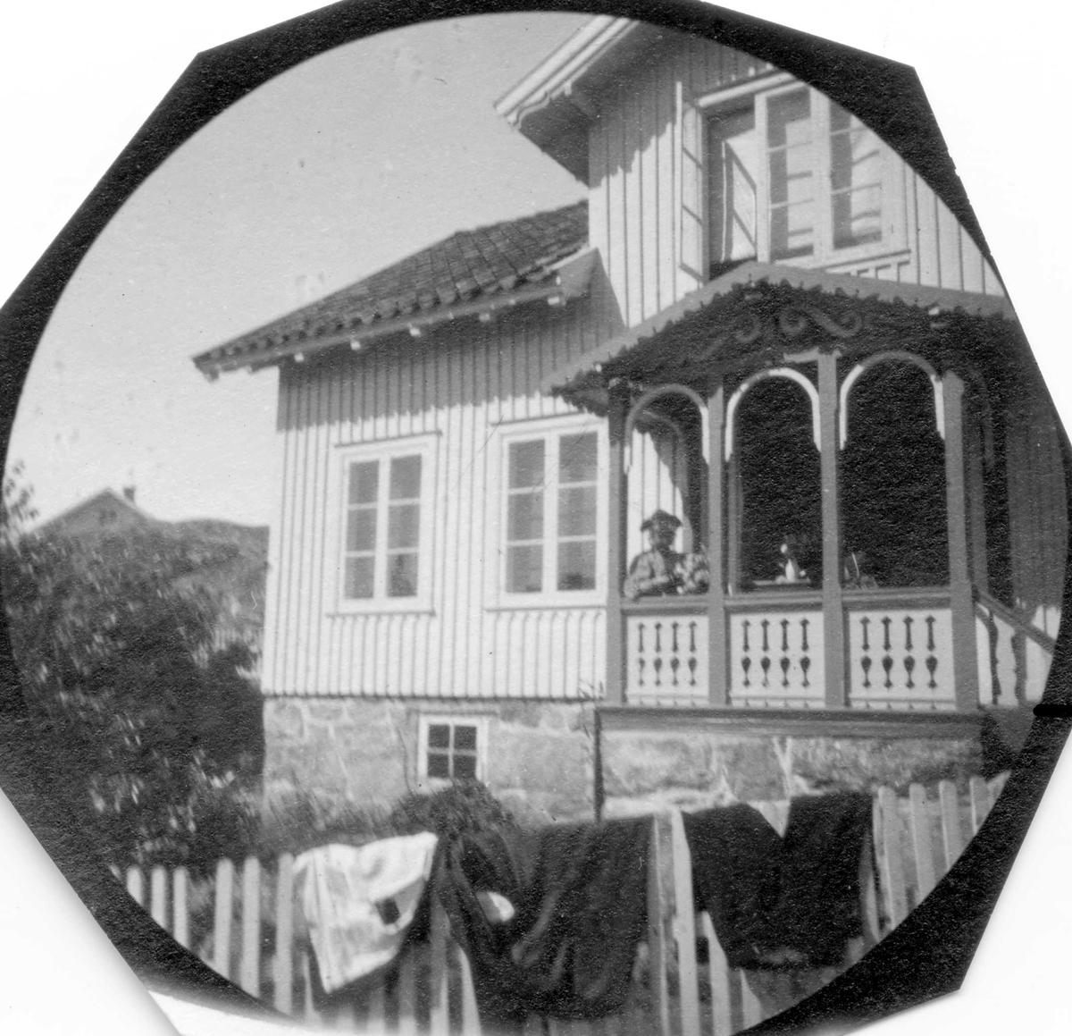 Fredrik Carl Mülertz Størmer, Frk. Maren Astrup på veranda i Ula, Tjølling, Larvik, Vestfold. Klær henger på gjerdet til tørk. Sveitserstil.